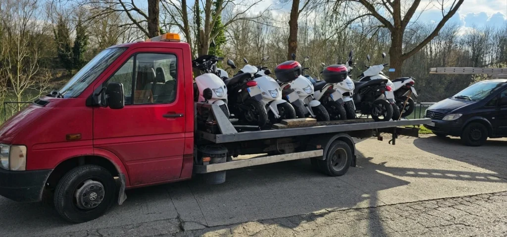 Scooters transportés sur une dépanneuse rouge, illustrant le service de rachat de moto et scooter de RepriseVehicule.fr.