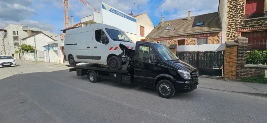 Dépanneuse plateau transportant un utilitaire blanc accidenté